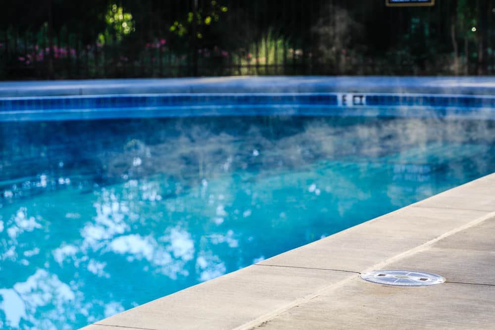 A steaming swimming pool with a concrete edge