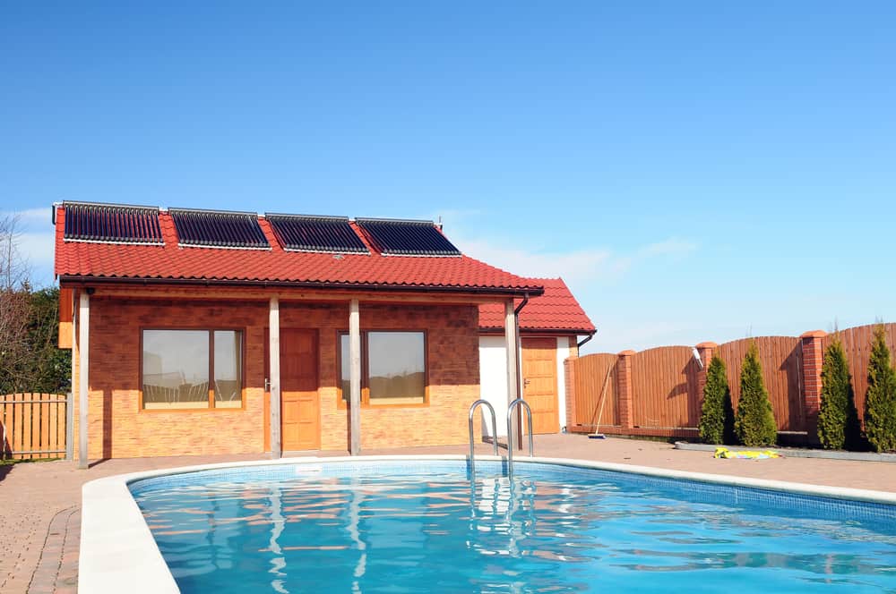 Solar heating array on roof of bungalow behind swimming pool