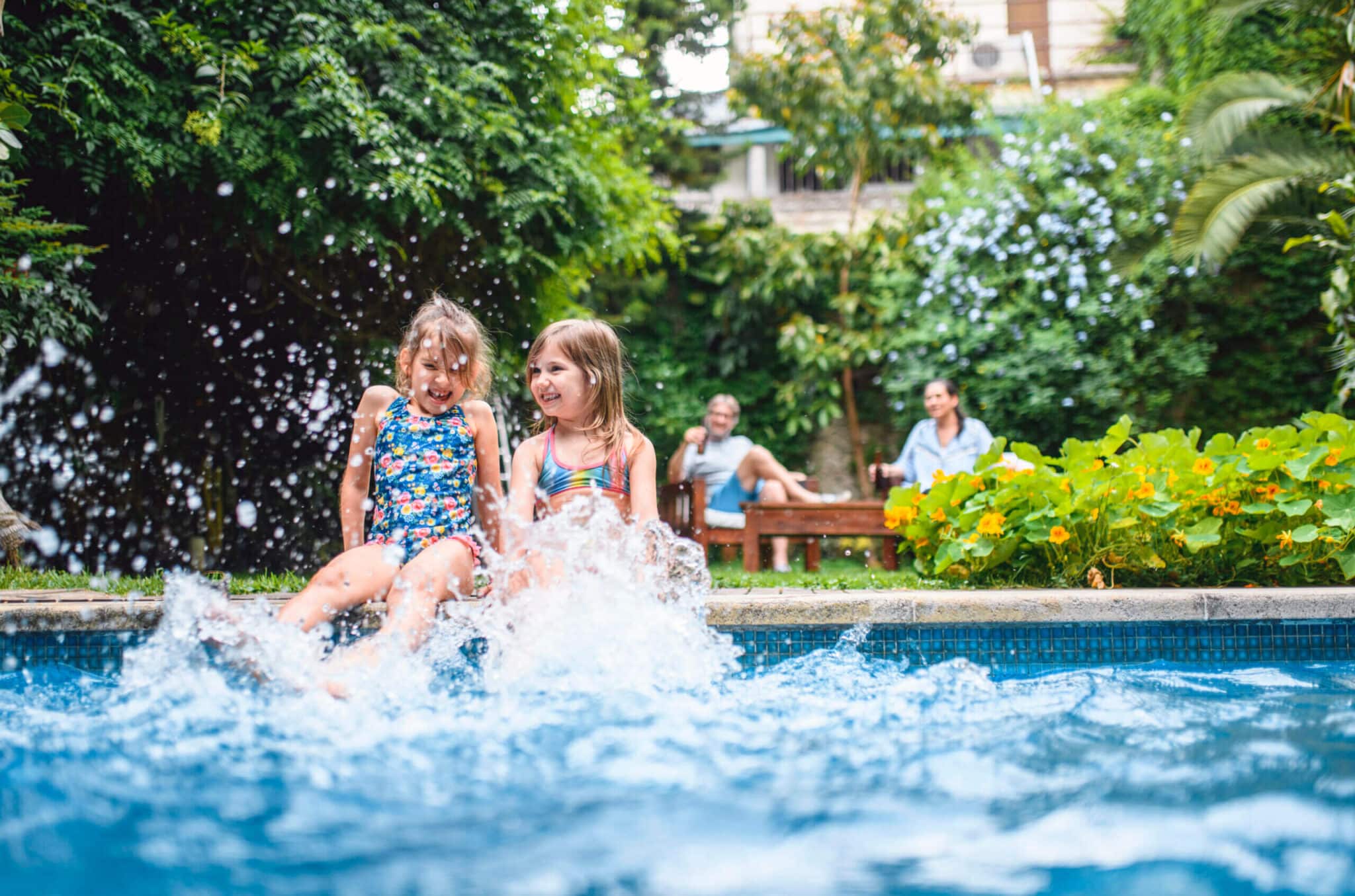 Carefree Young Sisters Splashing Pool Water with Legs